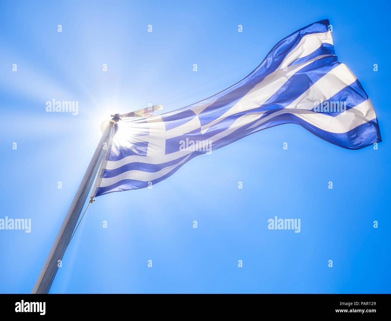 Official Flag Of Greece Waving On A Blue Sky And Sunlight Rays Stock official-flag-of-greece-waving-on-a-blue-sky-and-sunlight-rays-stock