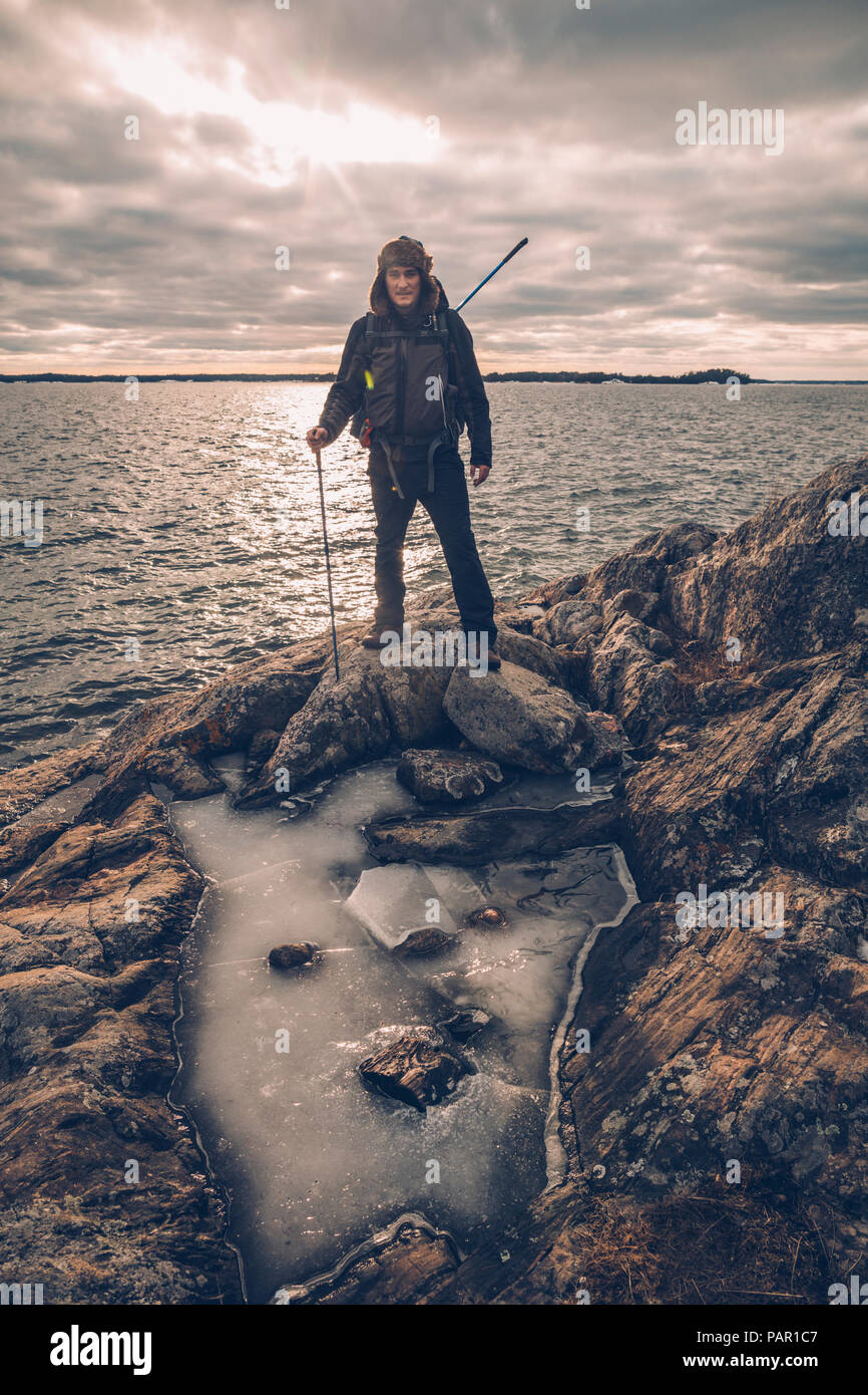 Sweden, Sodermanland, backpacker standing at the seashore under cloudy sky Stock Photo