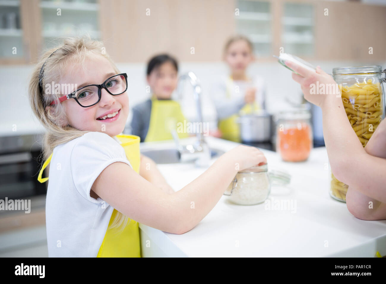 Portrait of smiling schoolgirl with classmtes in cooking class Stock Photo