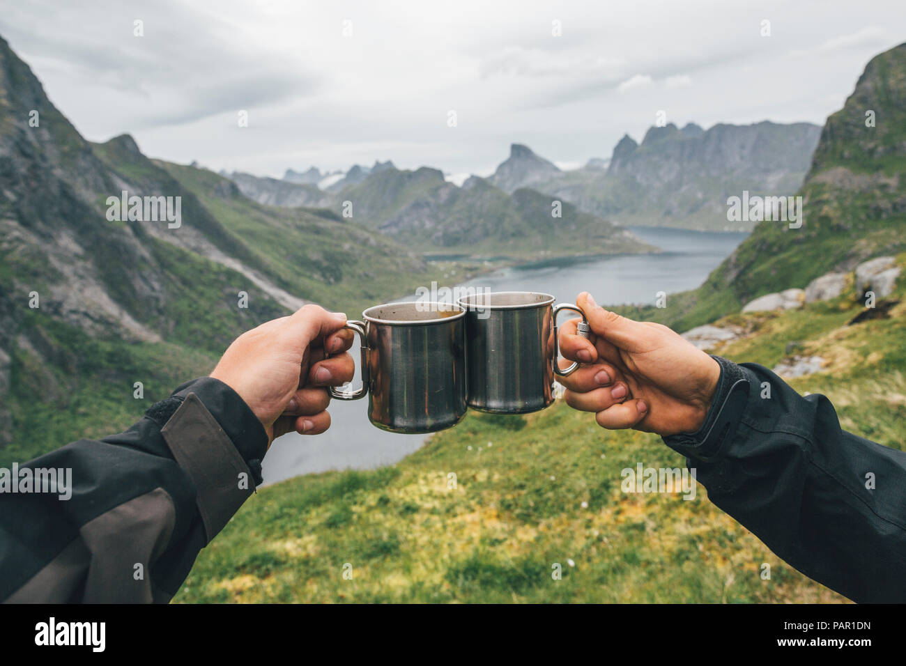 Norway, Lofoten, Moskenesoy, Two people toasting with tin cups Stock Photo