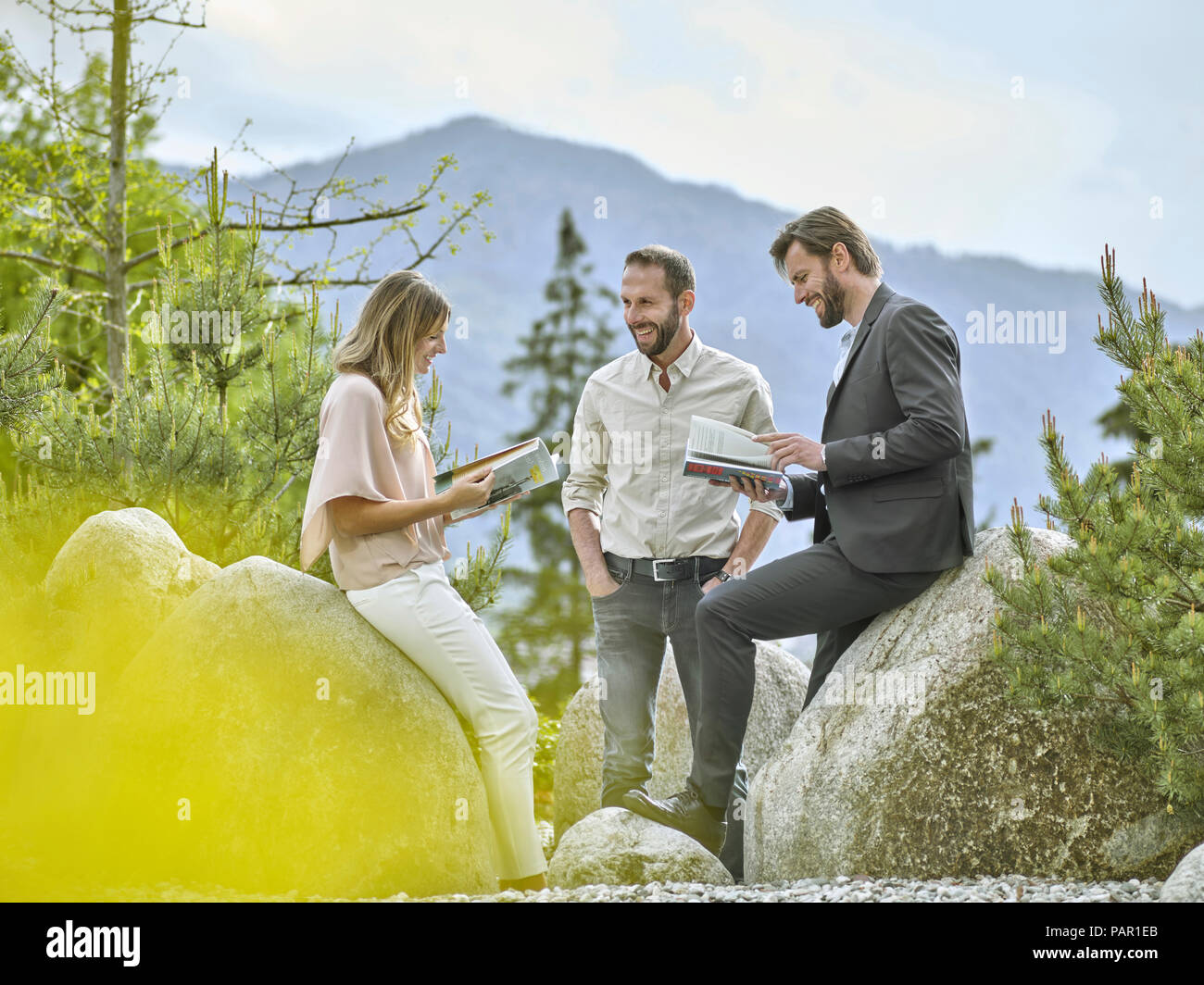 Smiling colleagues with magazines having a break at rocks Stock Photo