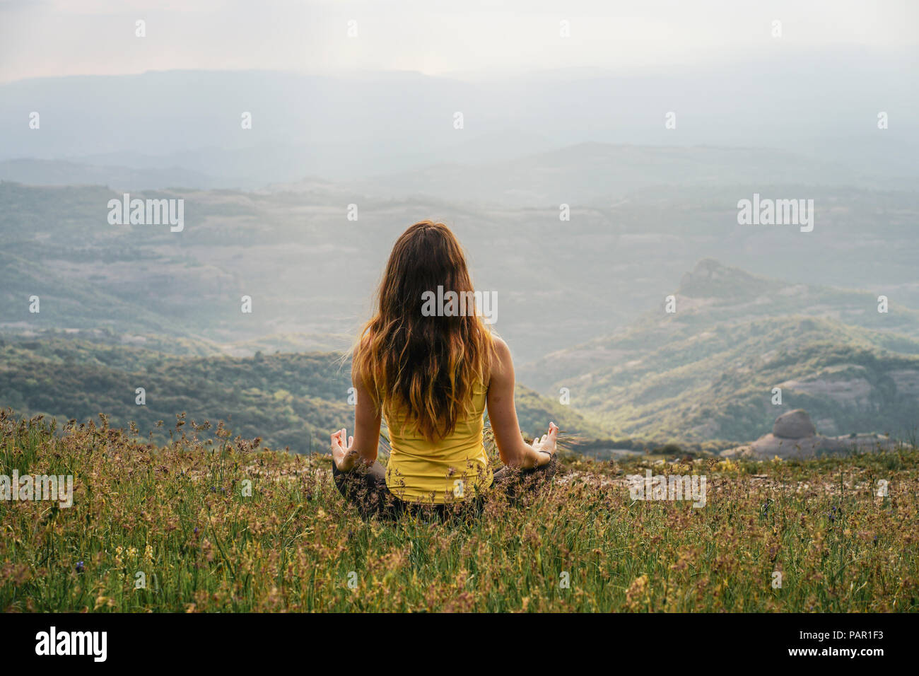 Spain, Barcelona, back view of young woman practising yoga on Montcau Mountain Stock Photo