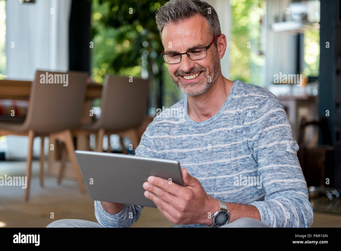 Smiling mature man at home using a tablet Stock Photo