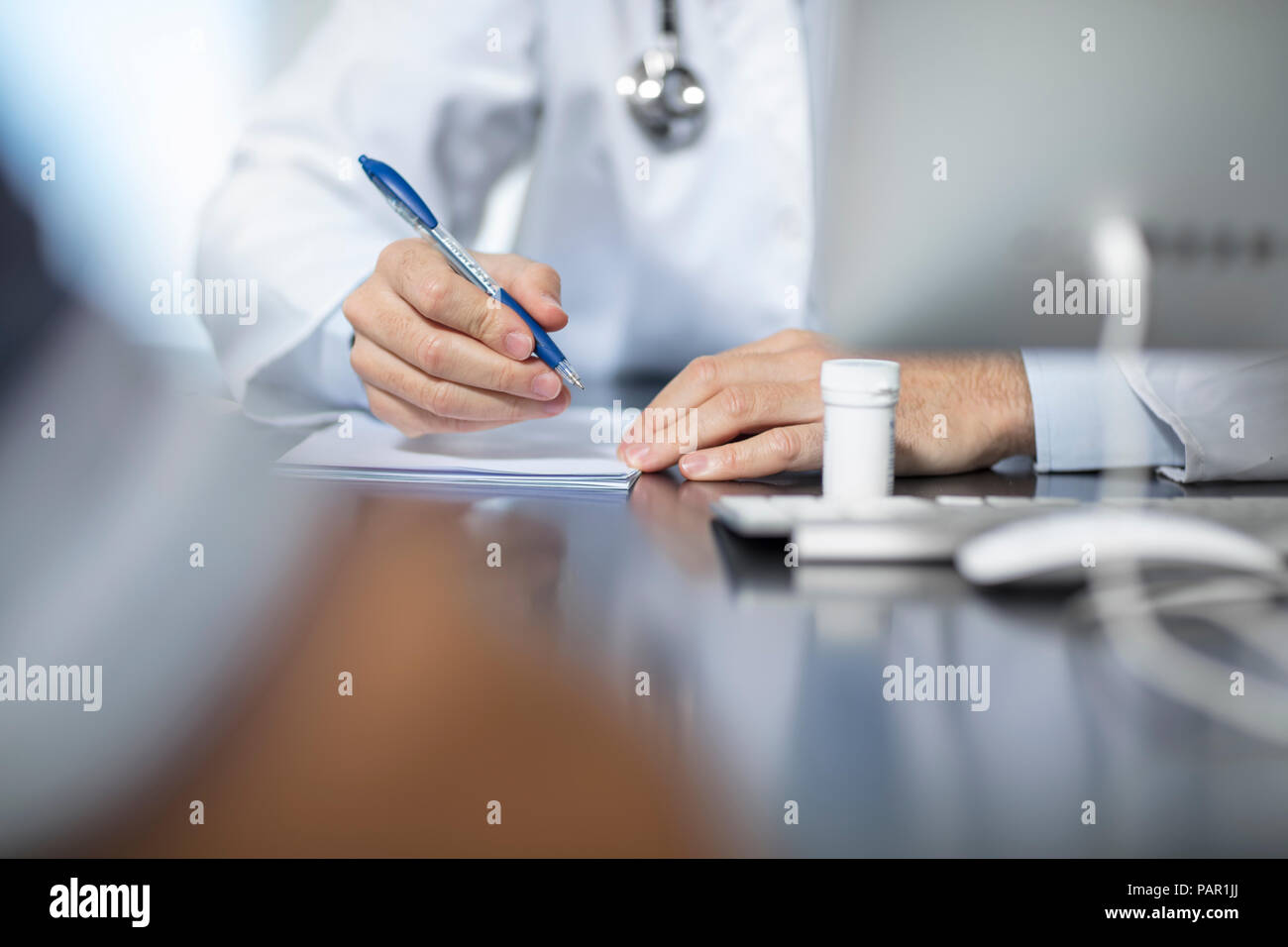 Doctor sitting at his desk taking notes Stock Photo