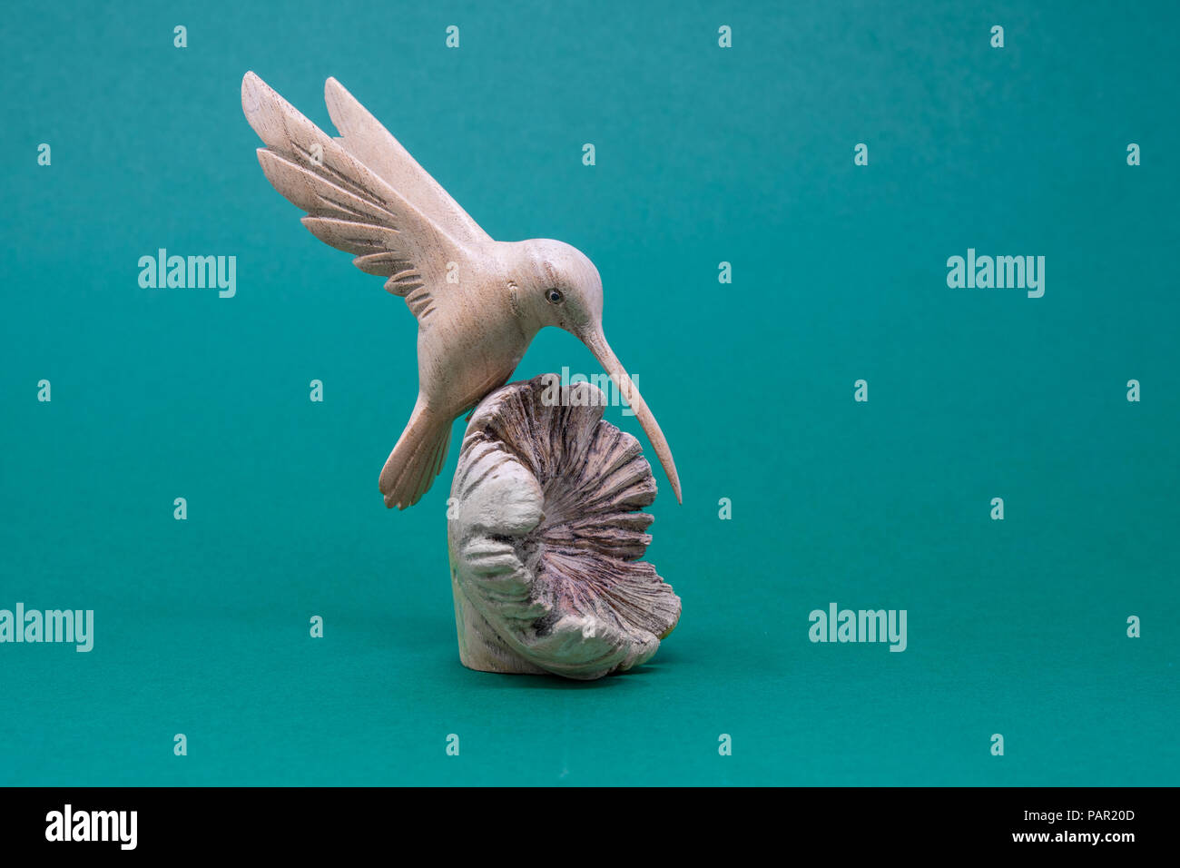 A carved wooden hummingbird landing on an open wooden shell, set on a ...