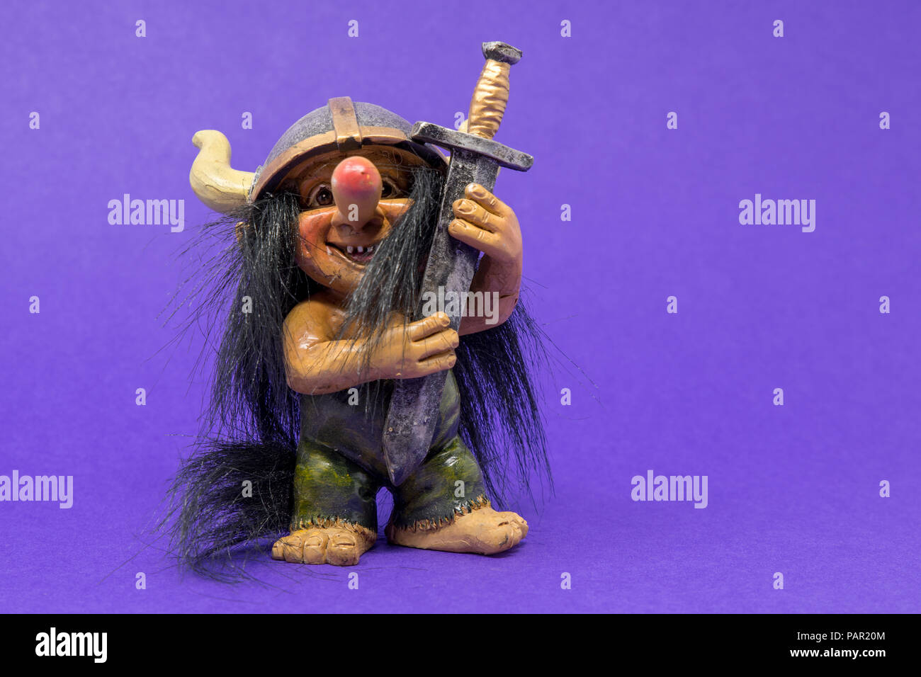 A toy, ornamental troll with a huge nose and big eyes wearing a viking  helmet holding a large, oversized sword Stock Photo - Alamy