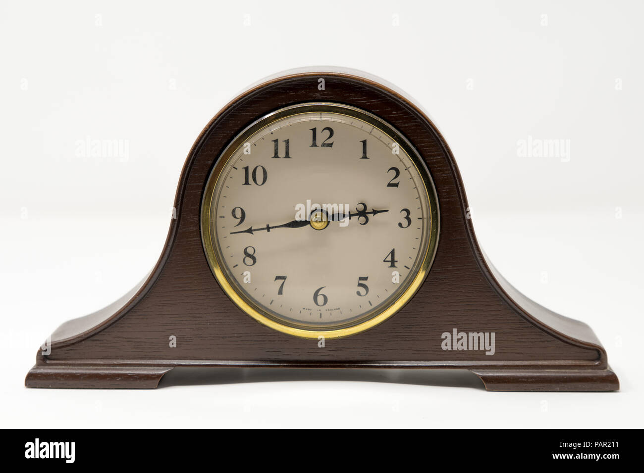 A traditional mantel clock with gold accents photographed against a white background Stock Photo