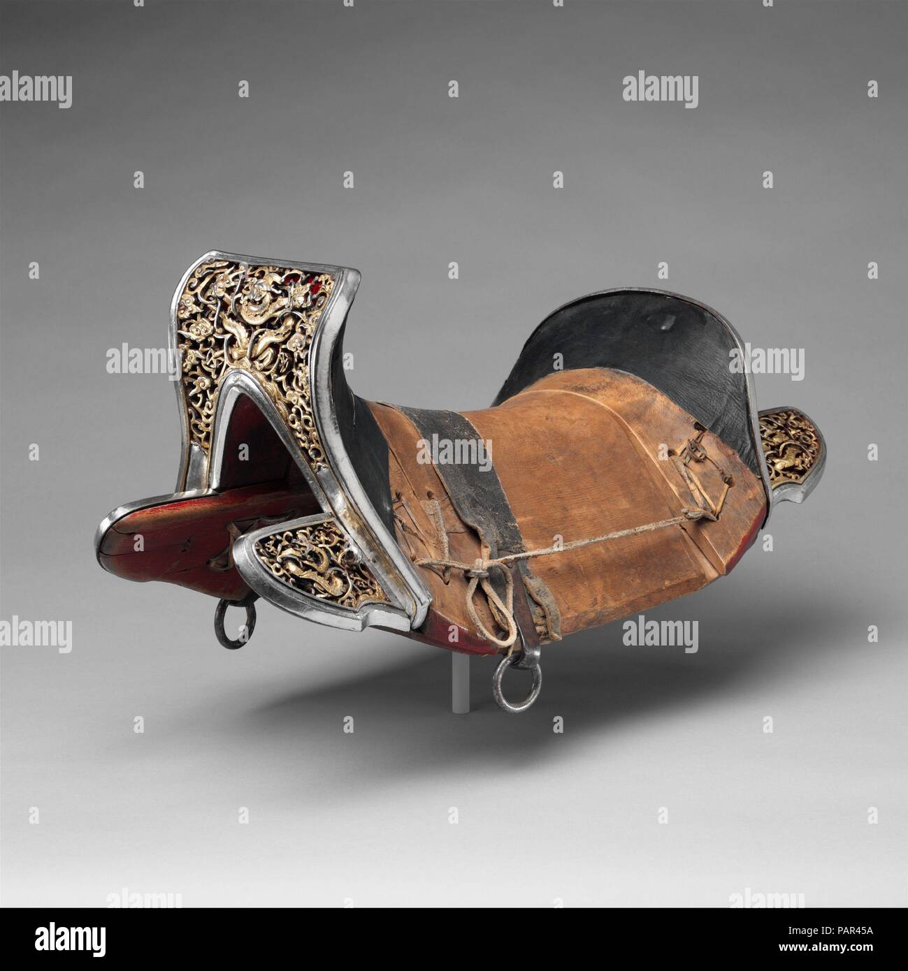 Saddle (gser sga). Culture: Eastern Tibetan or Chinese for the Tibetan market. Dimensions: H. 10 3/4 in. (27.3 cm); L. 22 1/2 in. (57.2 cm); W. 11 3/4 in. (29.8 cm). Date: 17th-18th century.  This saddle represents a particular form found in Tibet, one that is Chinese or strongly influenced by Chinese types. It belongs to a small group of closely related saddles that may stem from a single workshop or reflect a specific type developed in one region. Notable features are the lively dragons, chiseled free from the scrollwork ground, and the unusual decorative technique involving silver damasceni Stock Photo