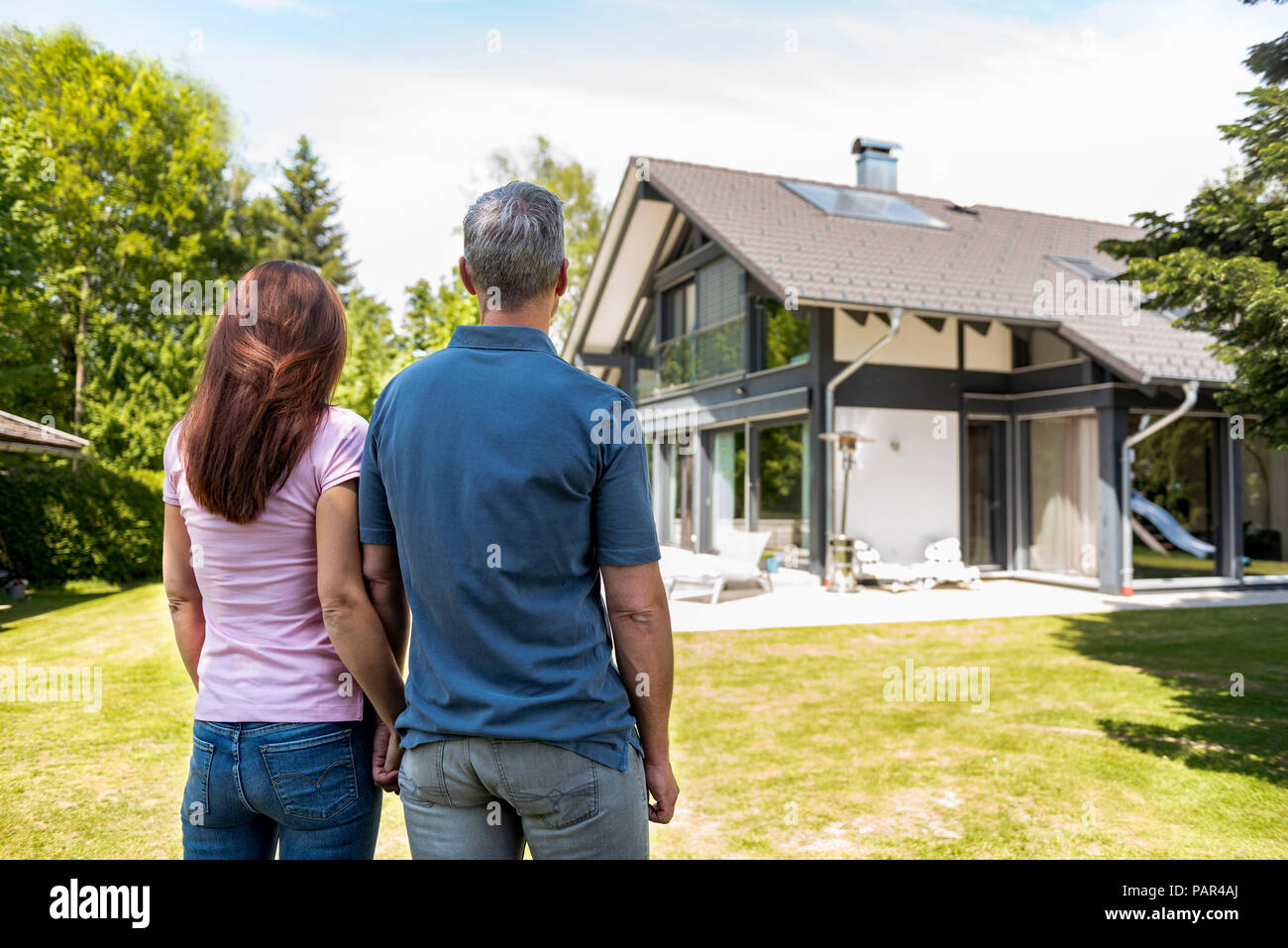 Couple standing hand in hand in garden of their home Stock Photo