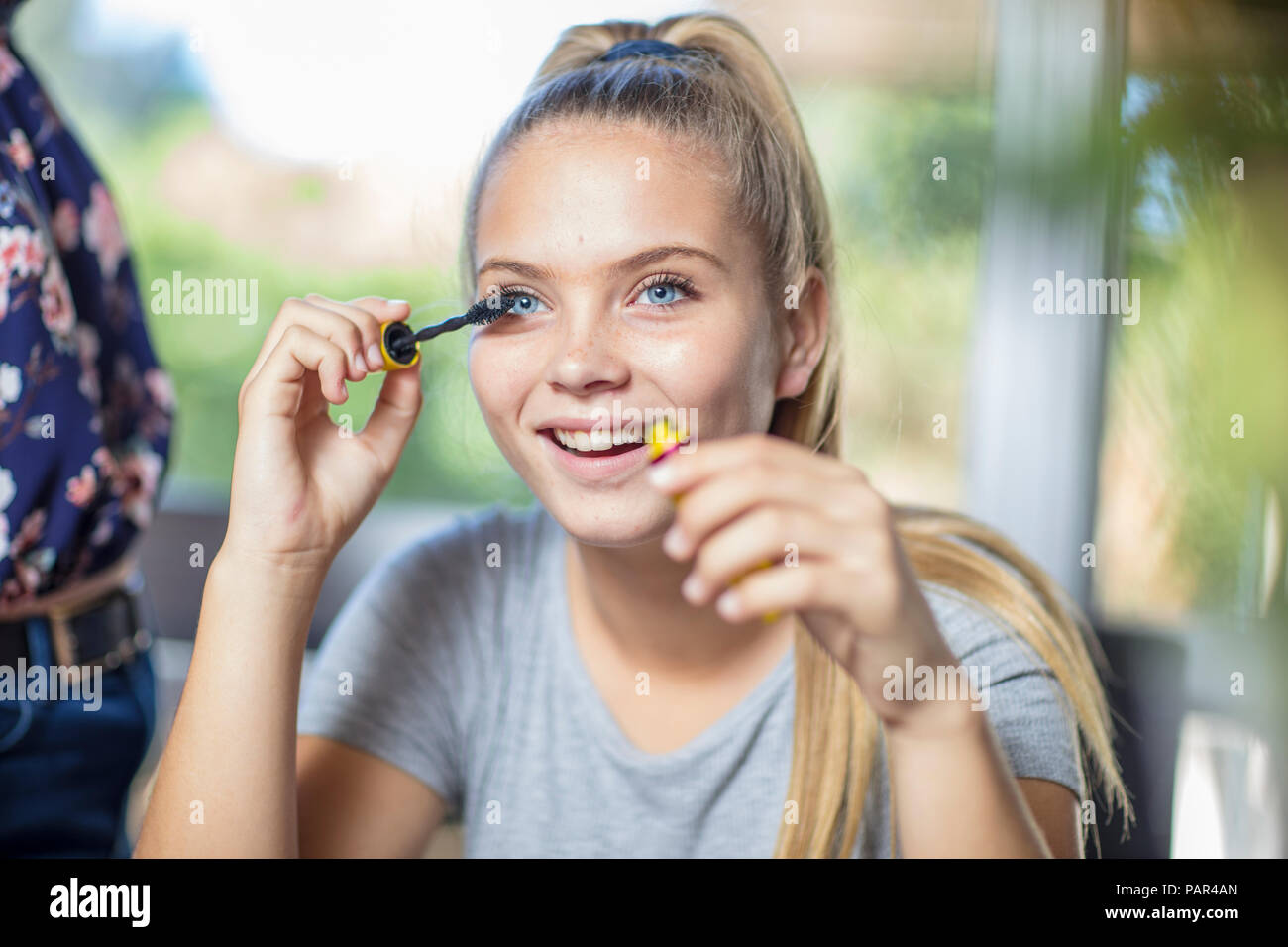 Portrait of smiling teenage girl applying mascara Stock Photo