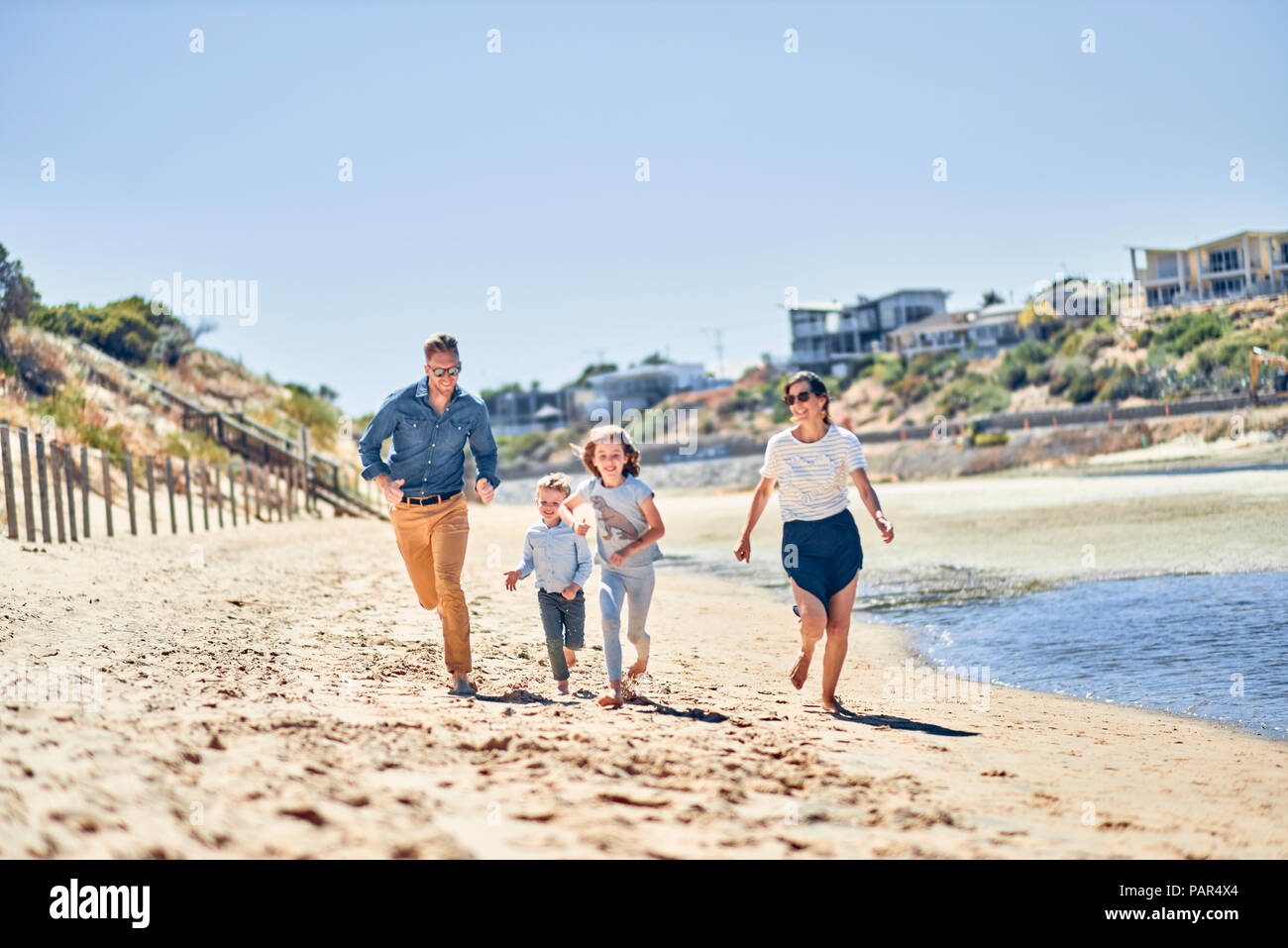 Australia, Adelaide, Onkaparinga River, happy family running on the beach together Stock Photo