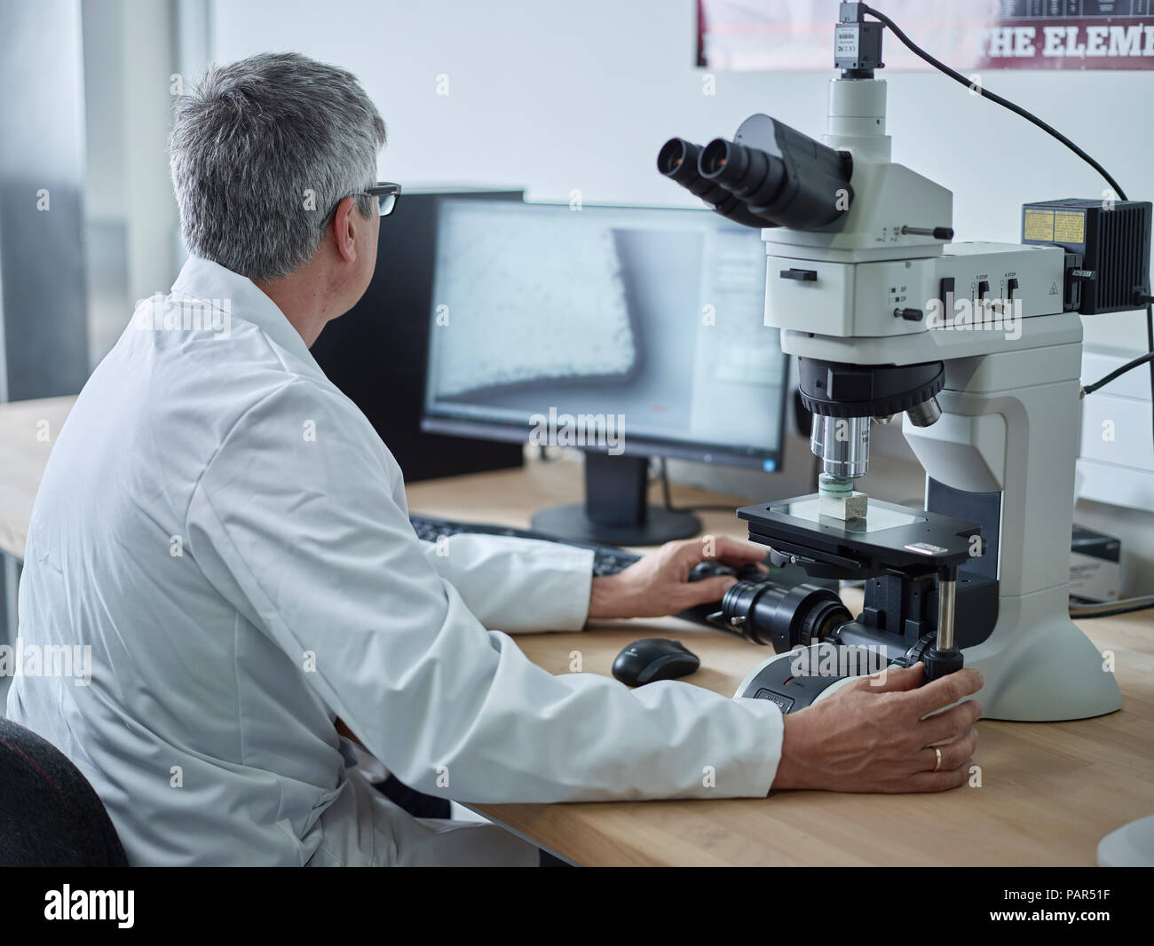 Physician working with microscope, looking on screen Stock Photo