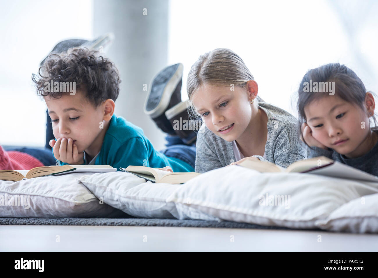 Pupils lying on the floor reading books in school break room Stock Photo