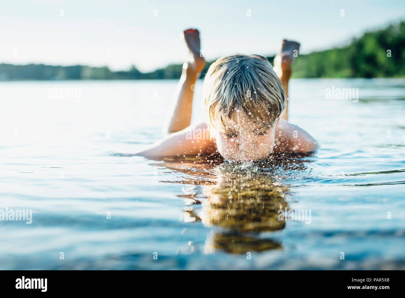 Boy in a lake blowing into water Stock Photo