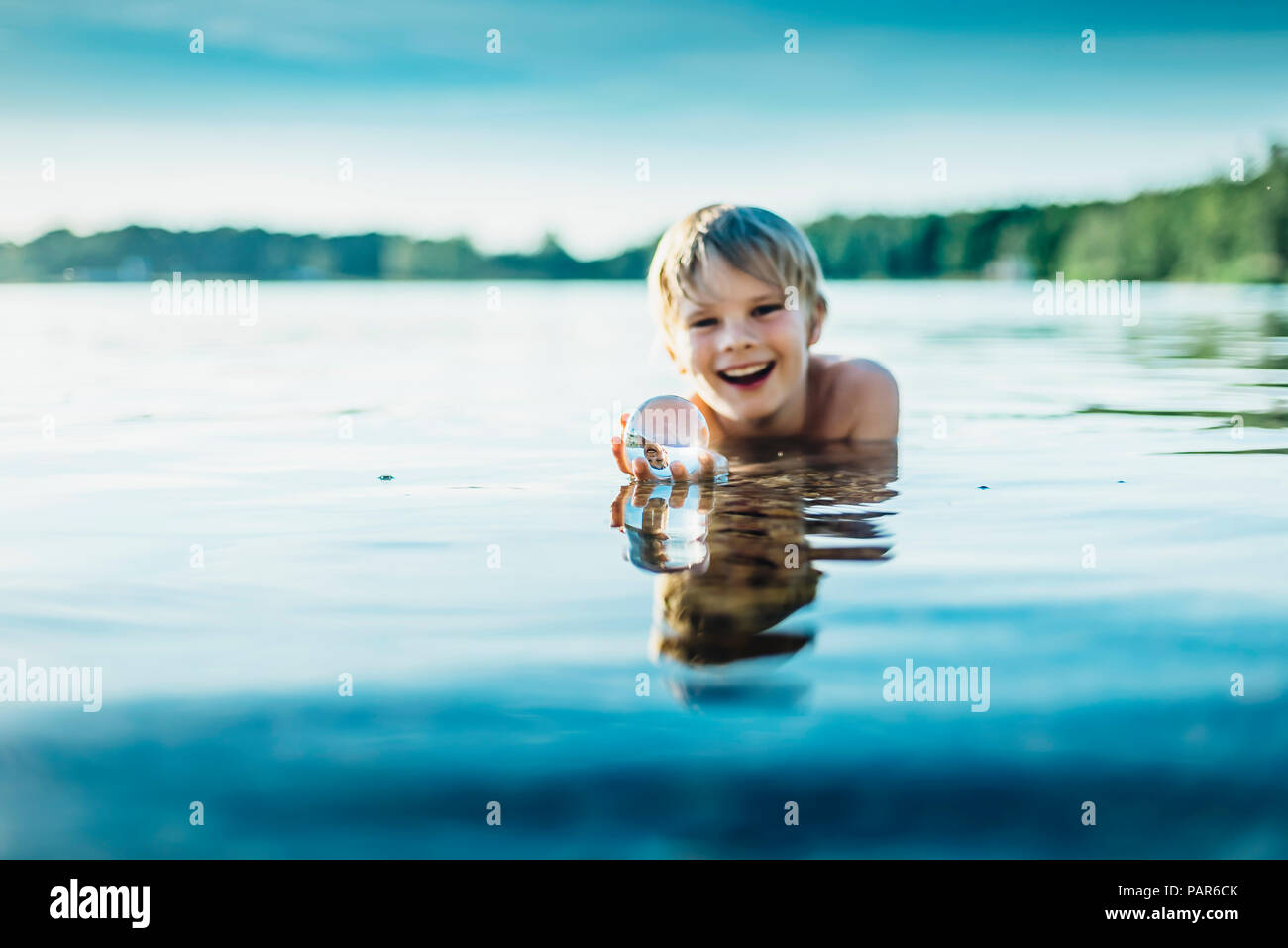 Portrait of happy boy in a lake holding tansparent sphere Stock Photo