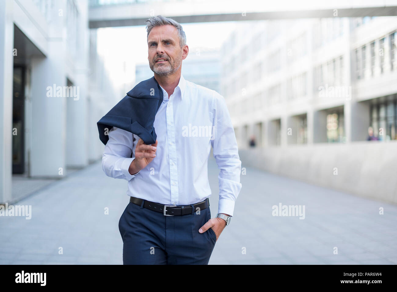 Portrait of businessman walking at courtyard of modern office building Stock Photo