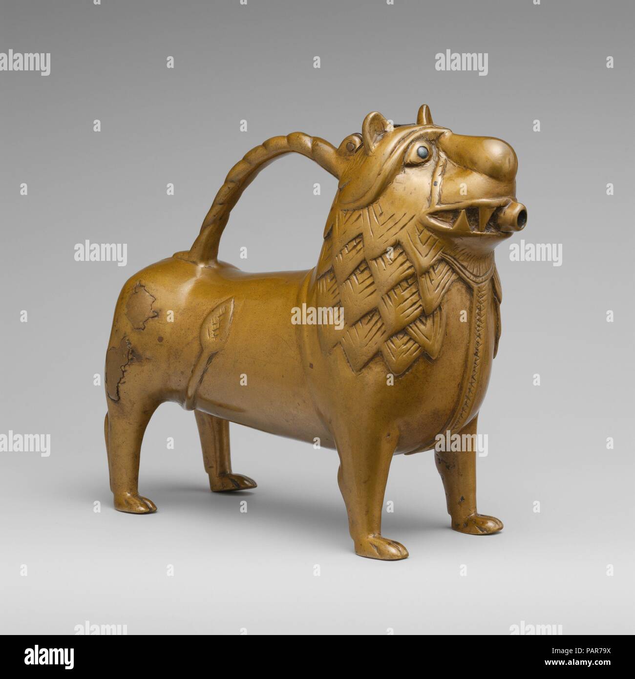 Aquamanile in the Form of a Lion. Culture: North German. Dimensions: Overall: 7 11/16 x 8 5/8 x 3 7/16 in. (19.5 x 21.9 x 8.7 cm)  Thickness PD: 9/100-1/10 in. (0.22-0.25 cm)  Weight PD: 72.9oz. (2067g). Date: 12th century.  The lion, because of its exceptional strength, was associated in the Middle Ages with Christ and was the animal most frequently employed for aquamanilia. The vessel was filled through the opening at the top of the head, and water was poured from the spout in the mouth. Museum: Metropolitan Museum of Art, New York, USA. Stock Photo