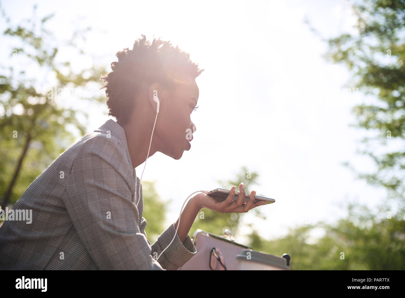 Businesswoman with earphones and smartphone at backlight Stock Photo