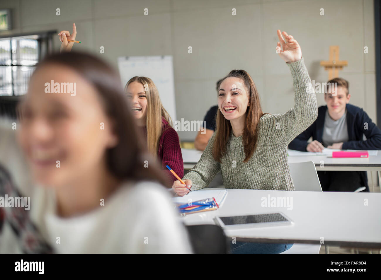 Happy teenage girls raising hands in class Stock Photo