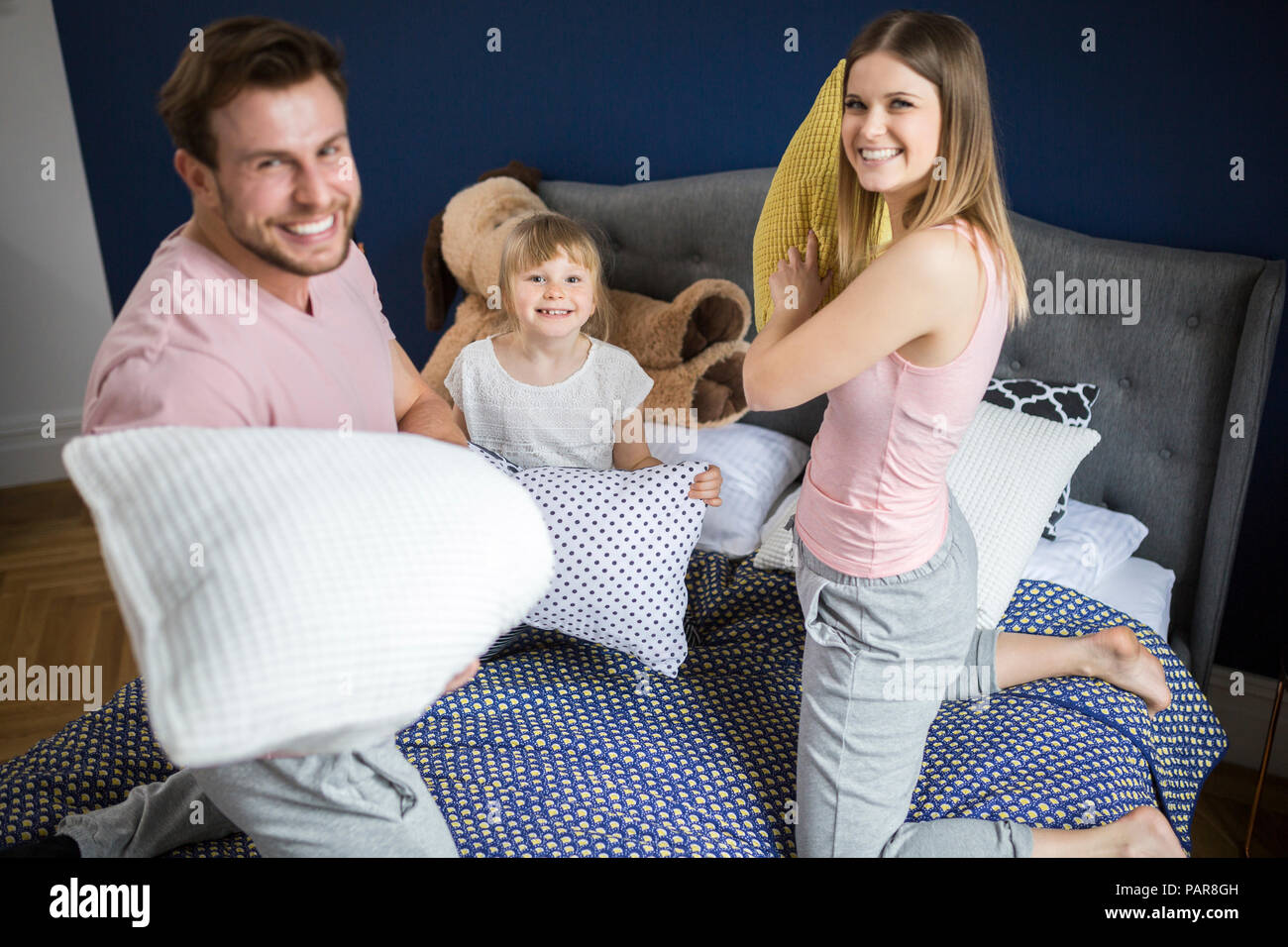 Happy family having fun in bedroom, having a pillow fight Stock Photo