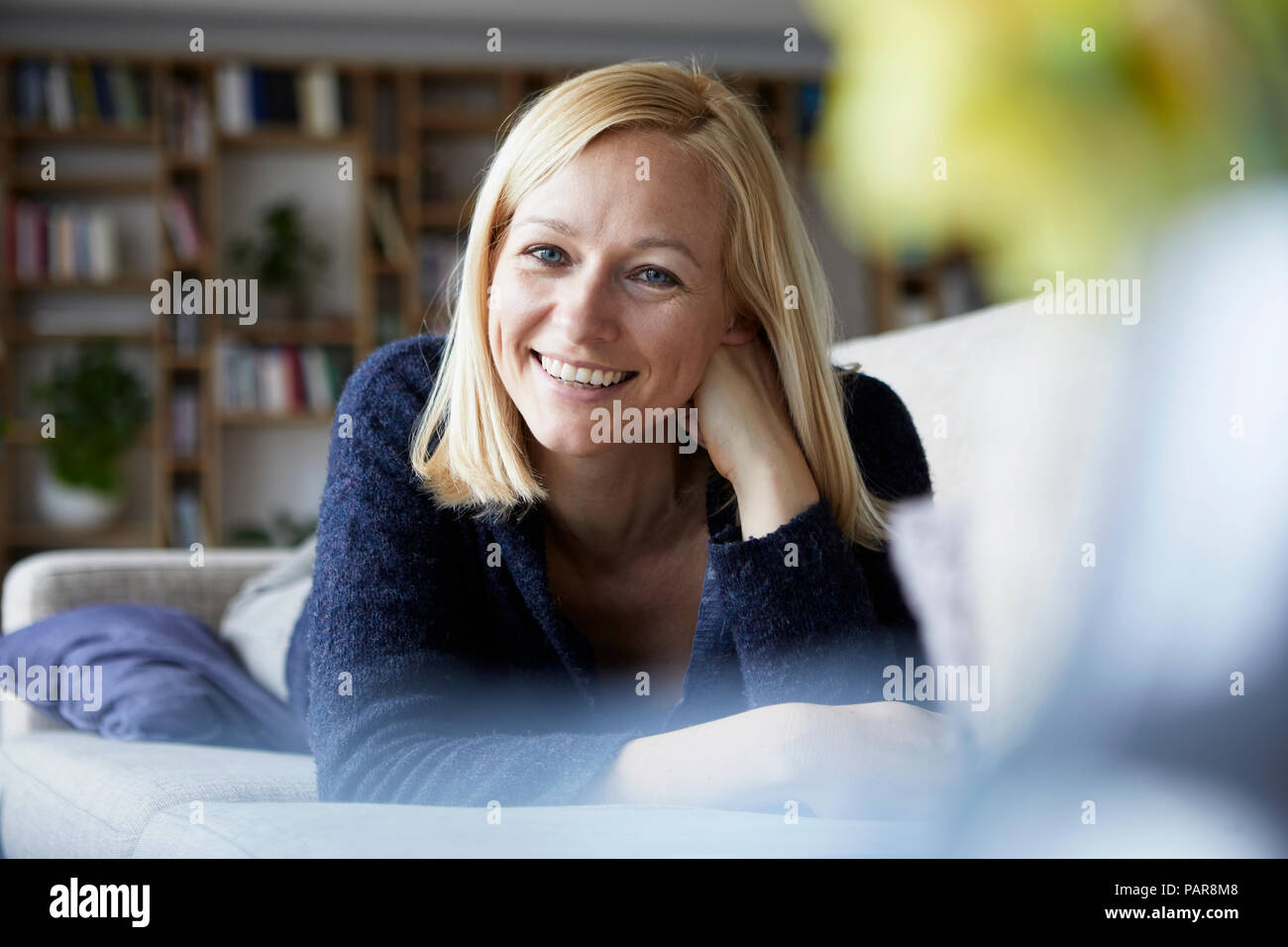 Woman relaxing at home, sitting on couch Stock Photo