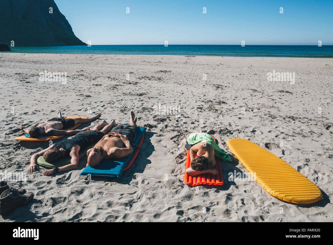 Norway, Lofoten, Moskenesoy, Friends sunbathing on Kvalvika Beach Stock Photo