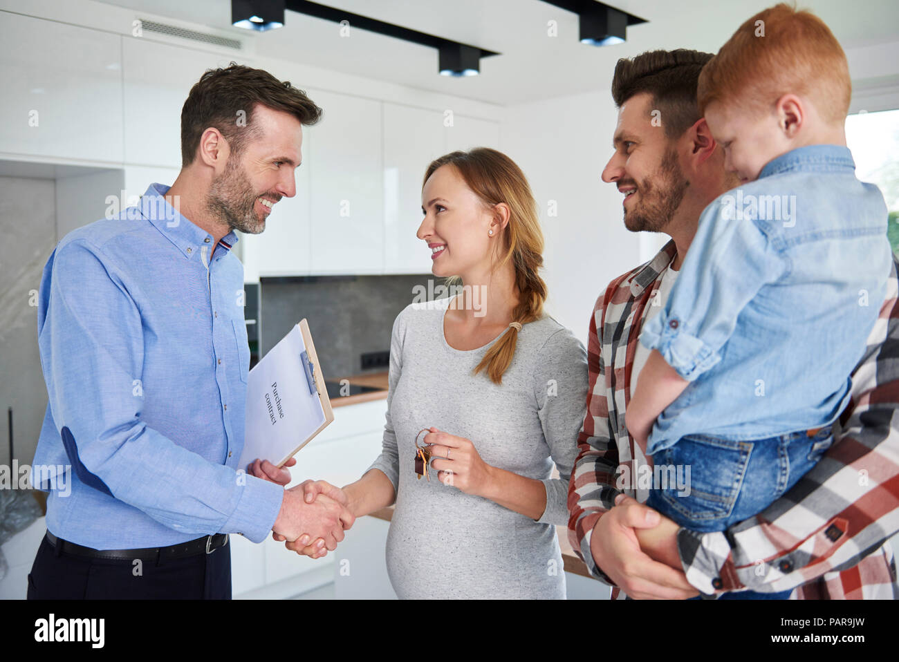 Family and real estate agent shaking hands in new apartment Stock Photo