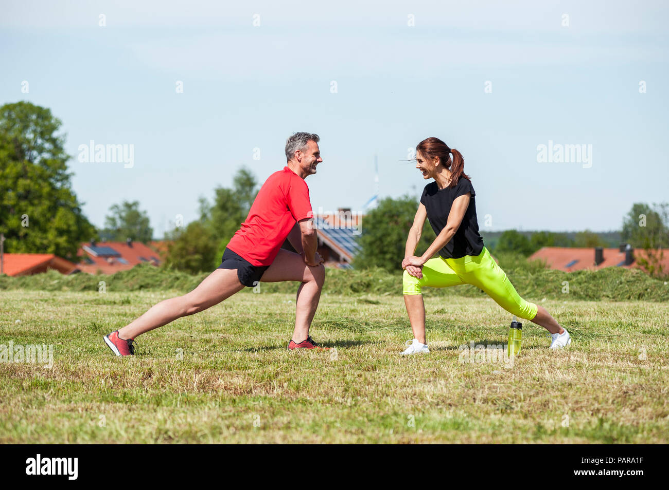 Couple doing stretching exercise on meadow Stock Photo