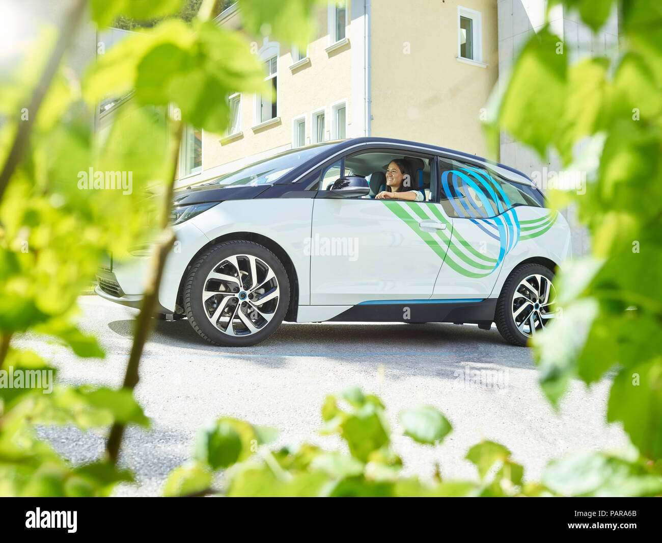 Smiling woman sitting in electric car Stock Photo
