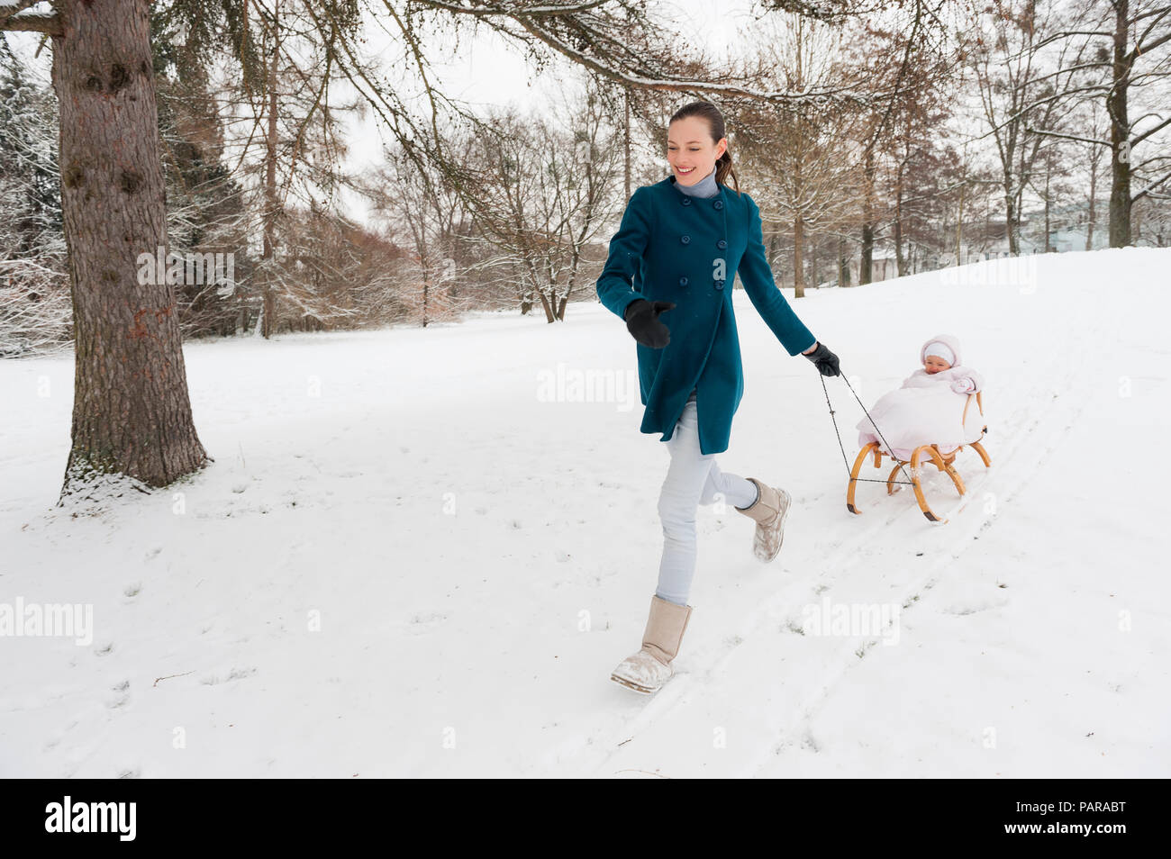 Mother pulling little daughter on sledge Stock Photo