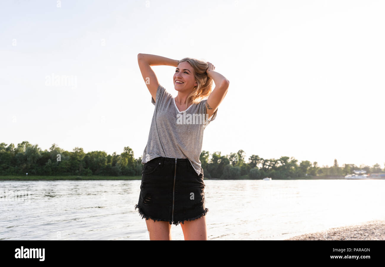 Young woman walking on riverside in the evening Stock Photo