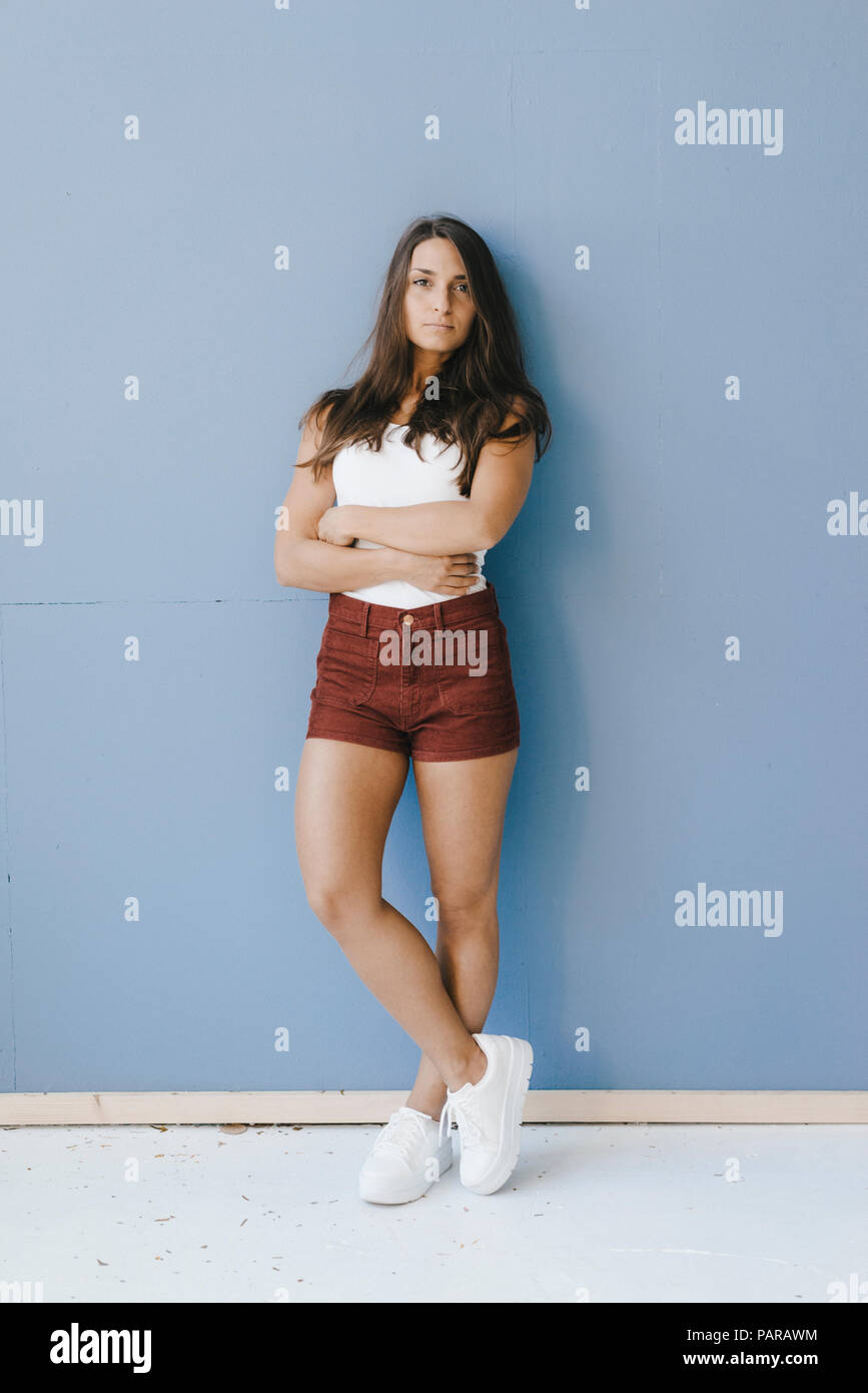 Woman leaning against wall arms crossed hi-res stock photography and