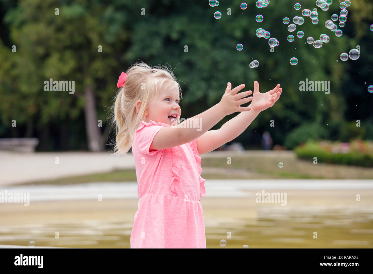 Three years old girl playing with soap bubbles Stock Photo