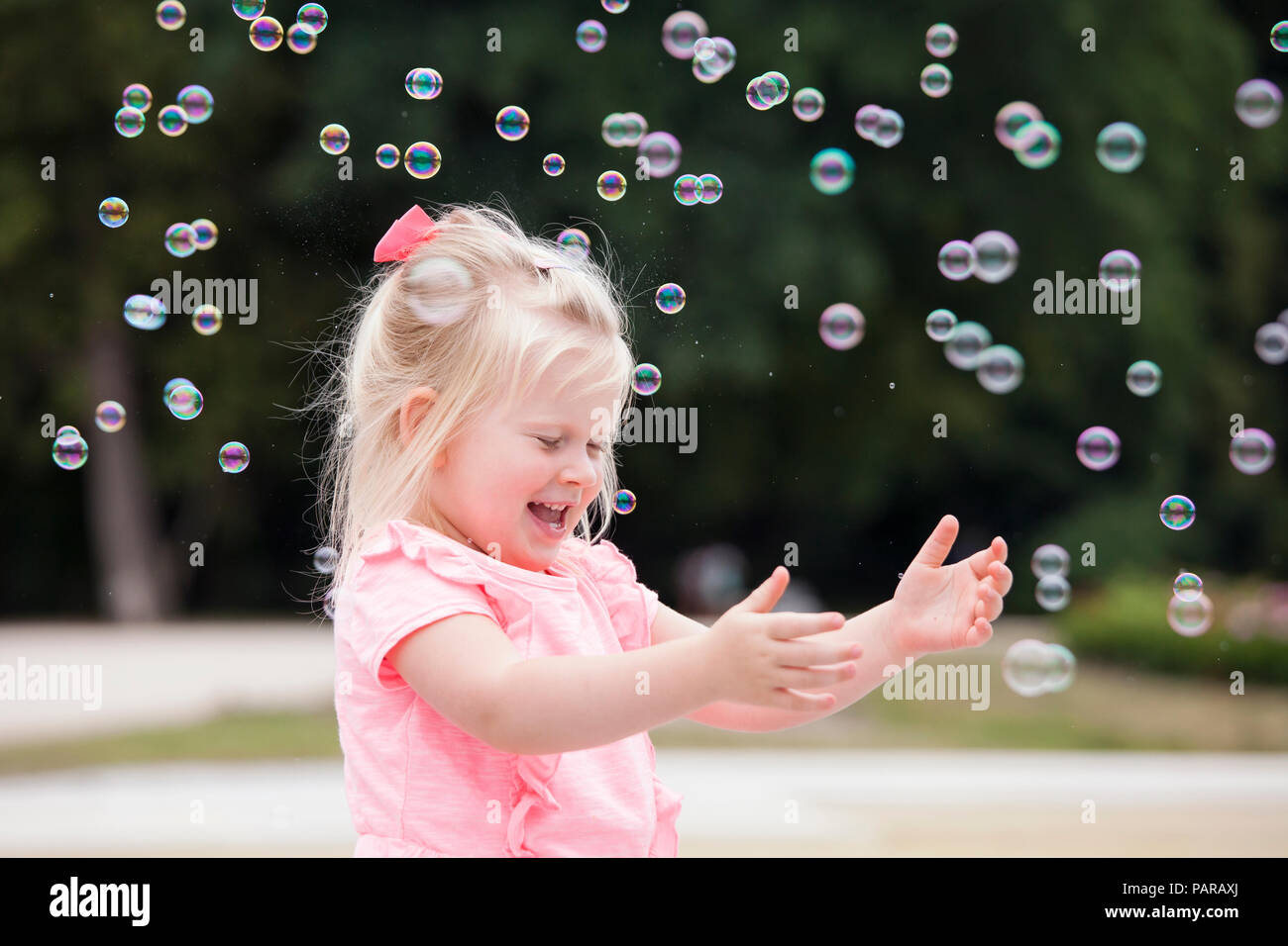 Three years old girl playing with soap bubbles Stock Photo