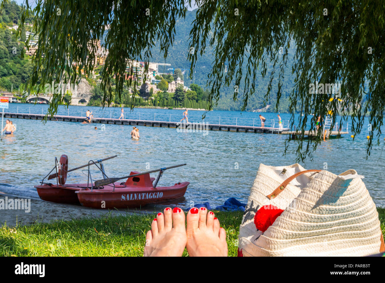 Chilling at the lake, relaxed concept, relaxing concept, switch off concept, sitting in grass, red toenails, beach bag, unplugged concept Stock Photo