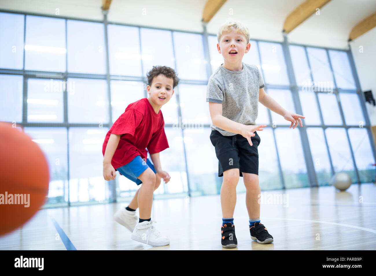 Two schoolboys playing basketball in gym class Stock Photo