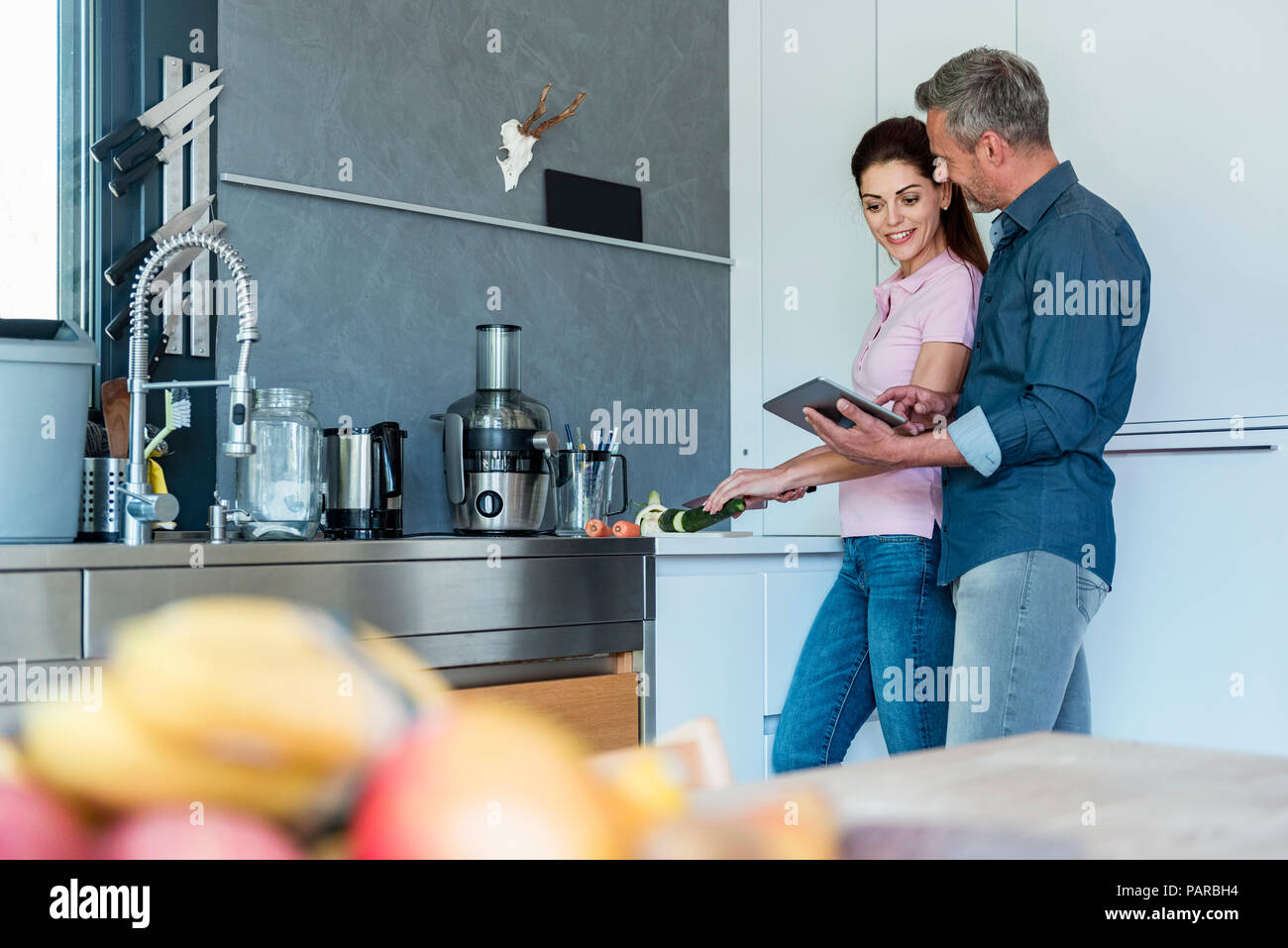 Couple in kitchen at home using a tablet Stock Photo