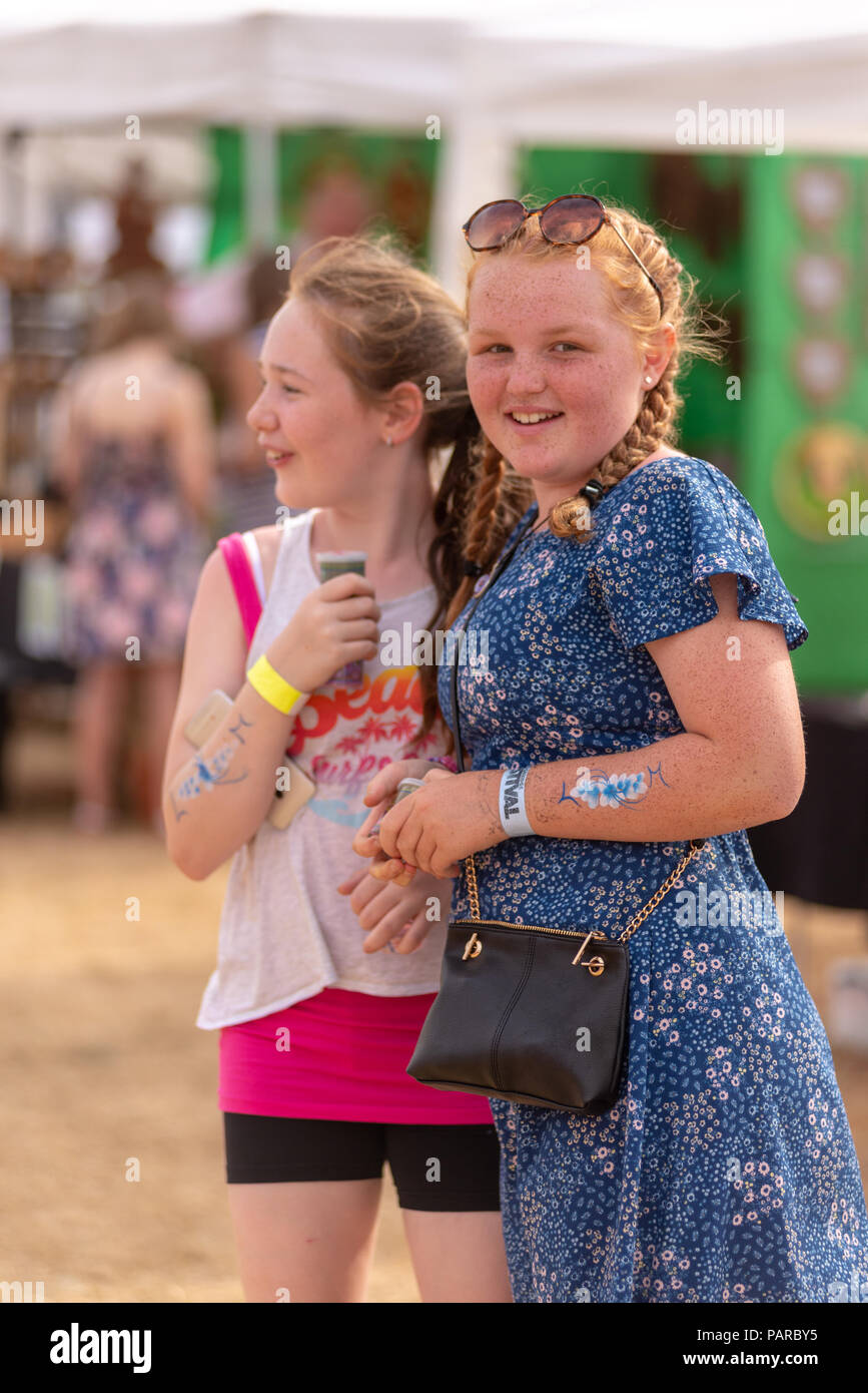 Two young teenage girls smiling at a family festival in summer. Stock Photo