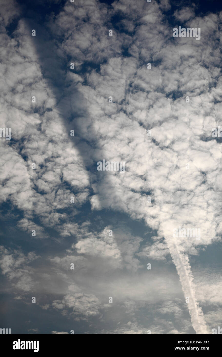 Chemtrail/contrail casting a shadow onto the clouds. Stock Photo