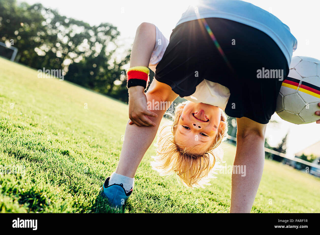 Boy on soccer field, bending over, looking through his legs Stock Photo