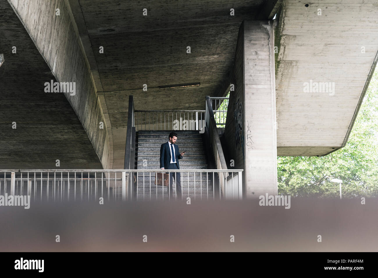 Businessman at underpass checking cell phone Stock Photo