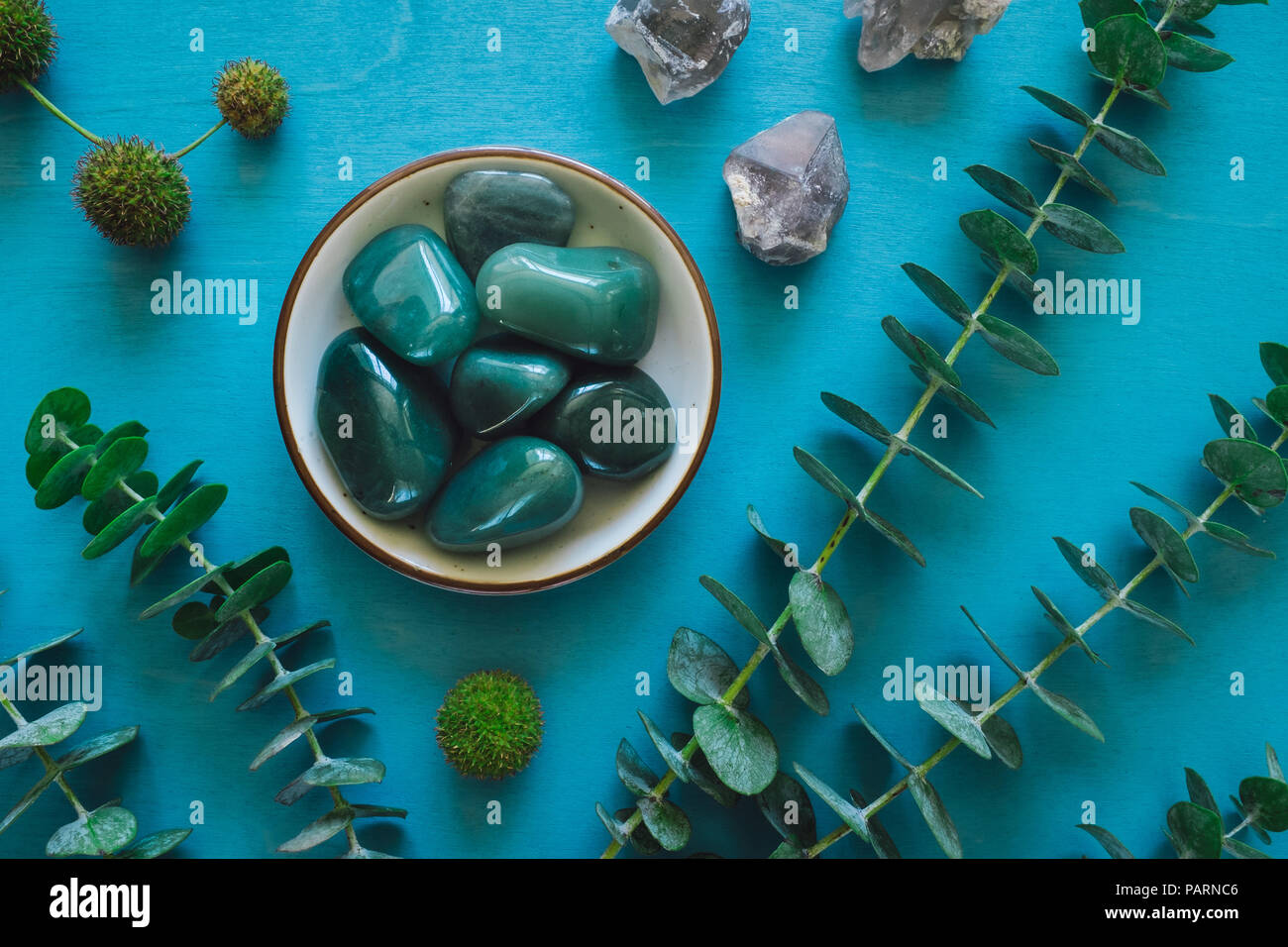 Green Aventurine with Quartz and Eucalyptus on Turquoise Table Stock Photo