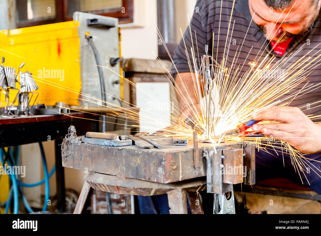 Sculptor is using arc welding to assembly metal sculpture without