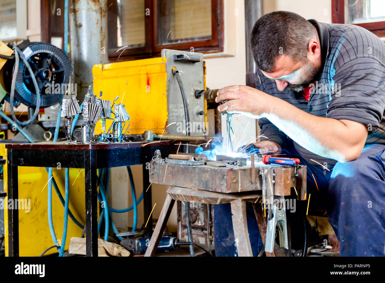 Sculptor is using arc welding to assembly metal sculpture without