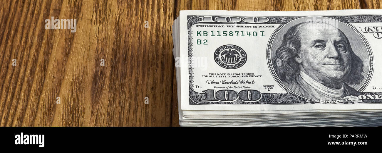 A stack of one hundred dollar American notes thrown on a wooden texture ...