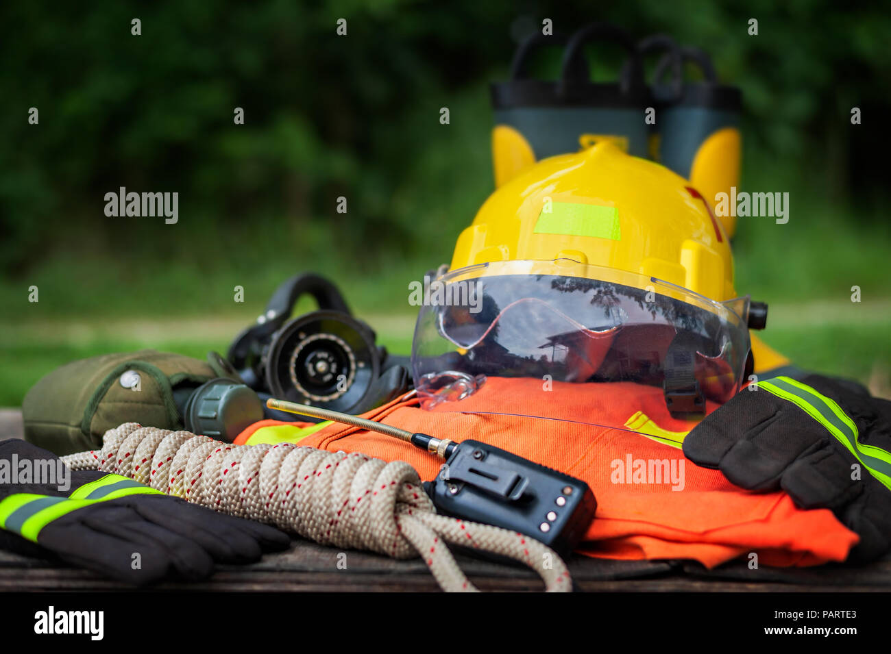 Outfit of Firefighter placed on wooden table background, Fire equipment concept. Stock Photo
