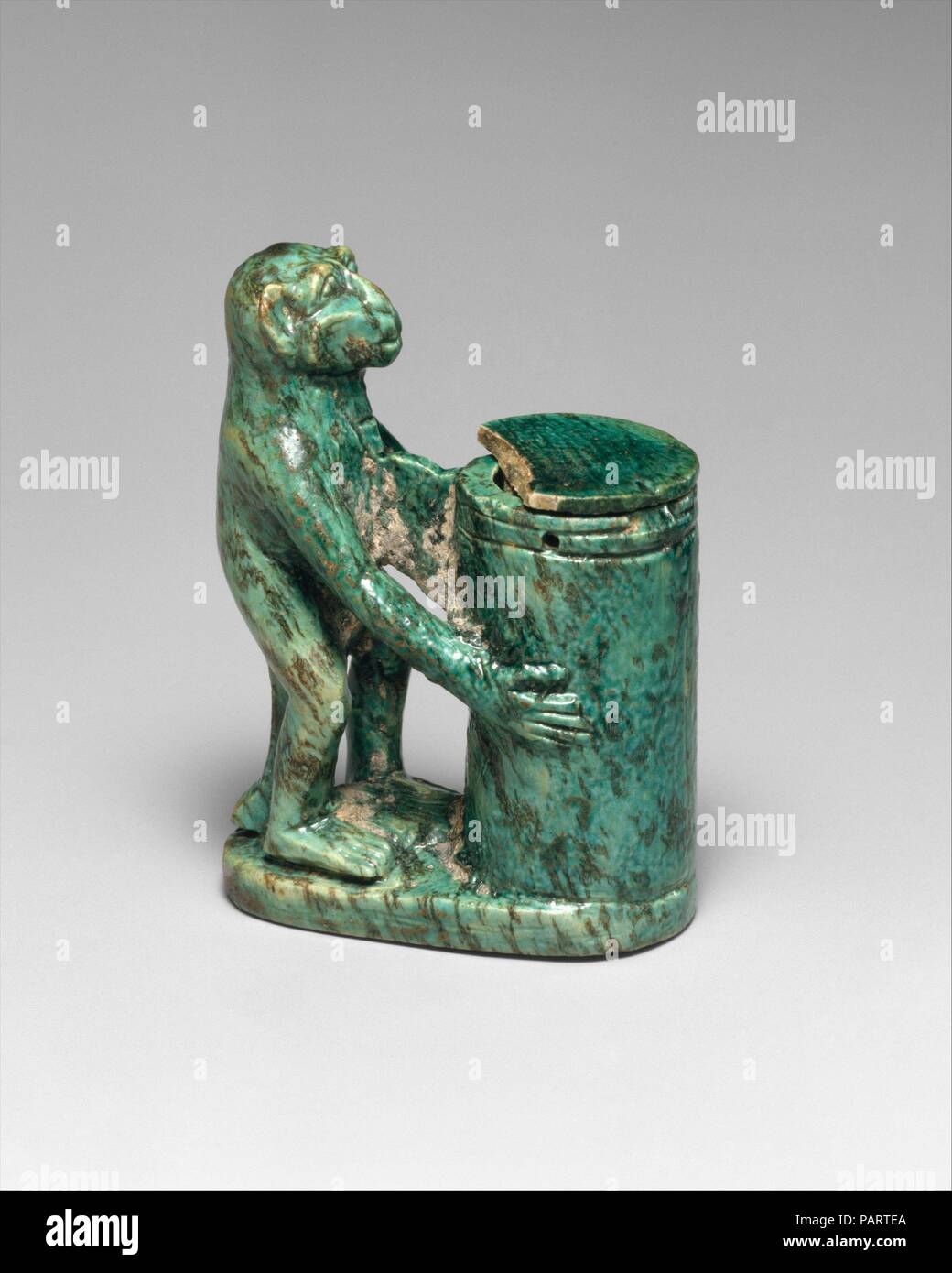 Kohl Tube in the Shape of a Monkey Holding a Vessel. Dimensions: h. 6 cm (2 3/8 in); w. 4.1 cm (1 5/8 in). Dynasty: Dynasty 18, early. Date: ca. 1550-1450 B.C..  The Egyptians' use of eye cosmetics to enhance beauty and for prophylactic purposes is well documented both in artistic representations and by the cosmetic vessels that have been preserved from the earliest times. The most common substance utilized in the New Kingdom was kohl, a dark gray powder made from galena. Kohl was frequently stored in decorated tubes with long, slim sticks made of polished wood or stone as applicators. As in e Stock Photo