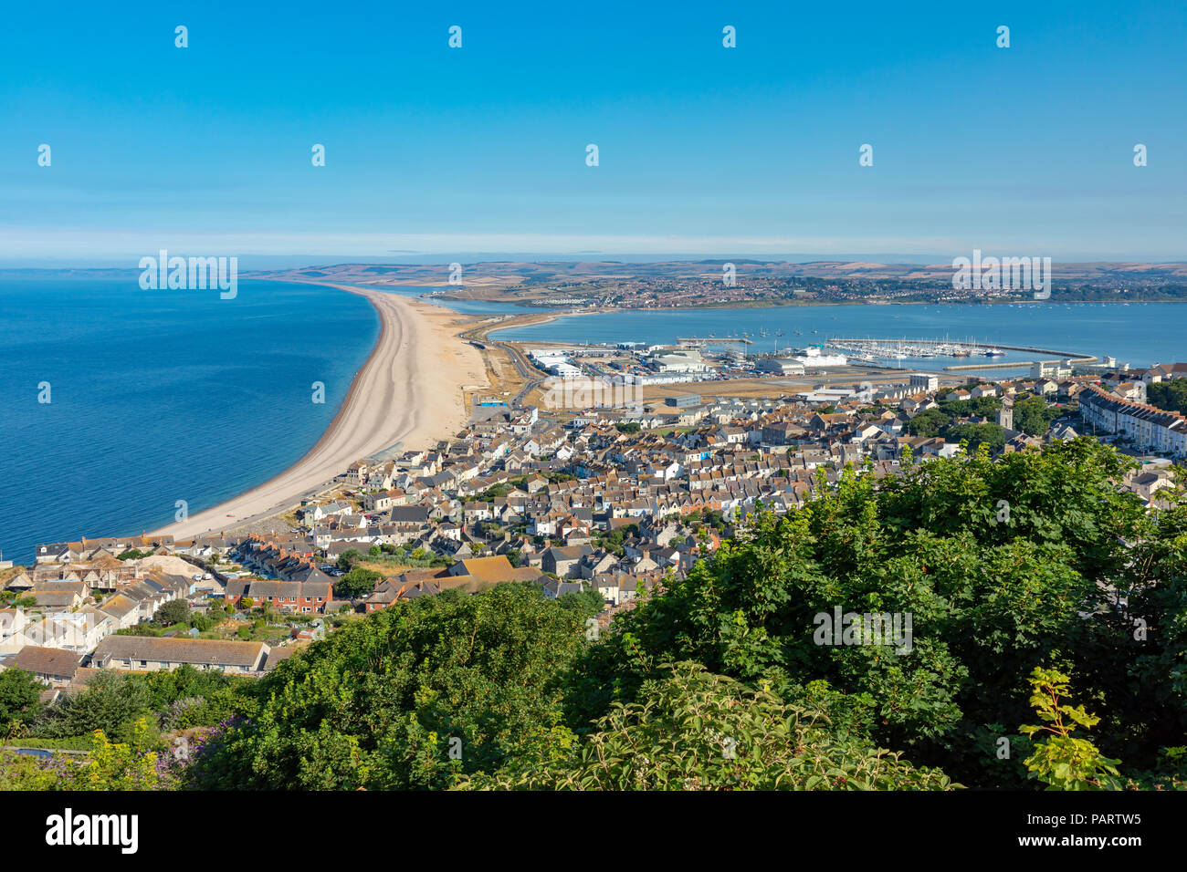 Portland Dorset England July 24, 2018 View from Portland Heights overlooking the town of Fortune's Well, showing Chesil Beach, Portland harbour and Th Stock Photo