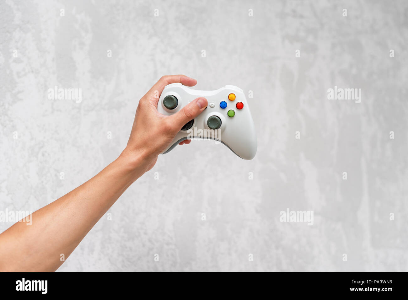 Hand holding gamepad on grey concrete background. Man with controller  playing video game at home. Leisure and entertainment. Video game console  contro Stock Photo - Alamy