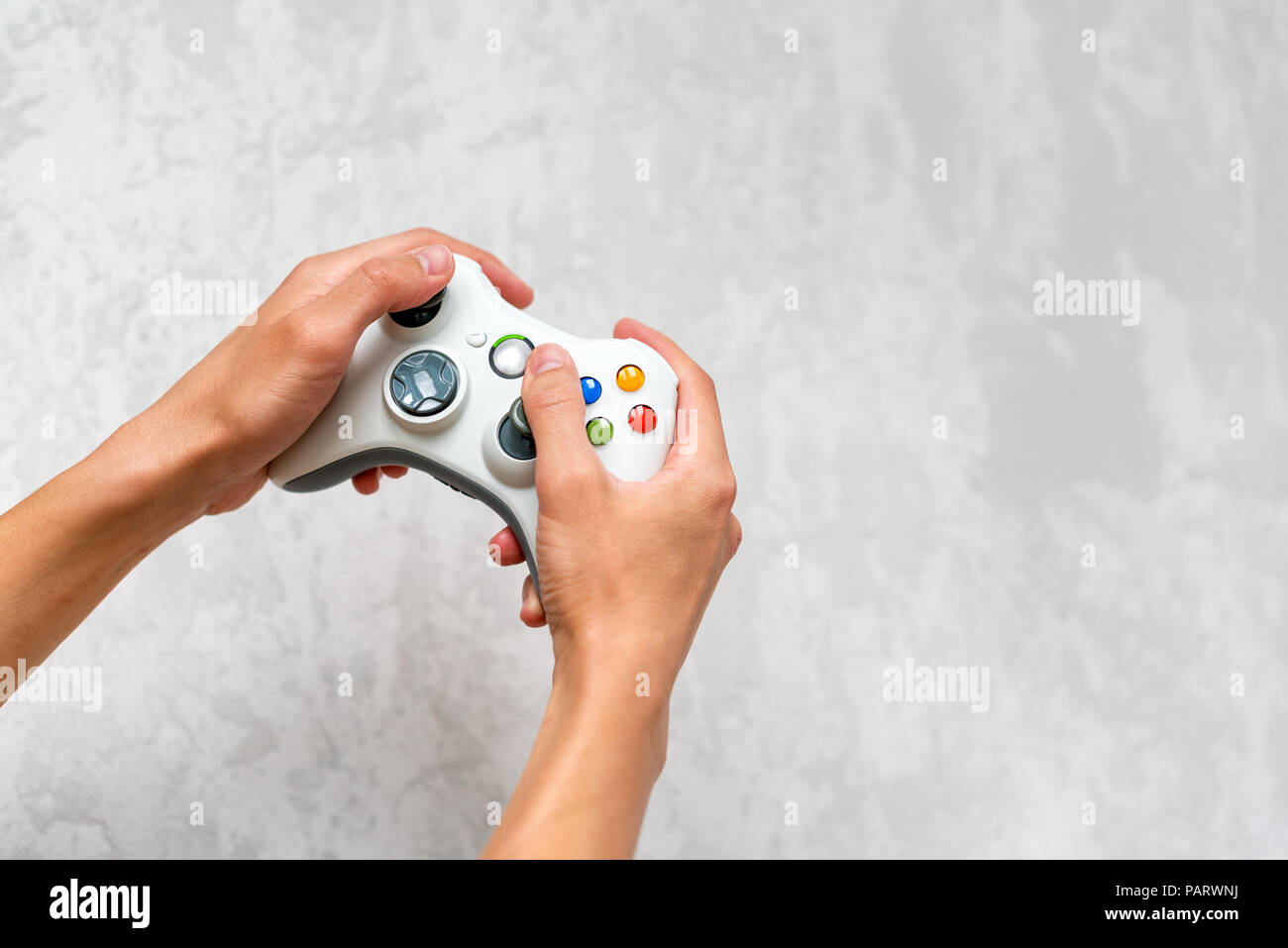 Hand holding gamepad on grey concrete background. Man with controller